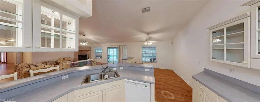Kitchen with a fireplace, white cabinetry, dishwasher, sink, and ceiling fan