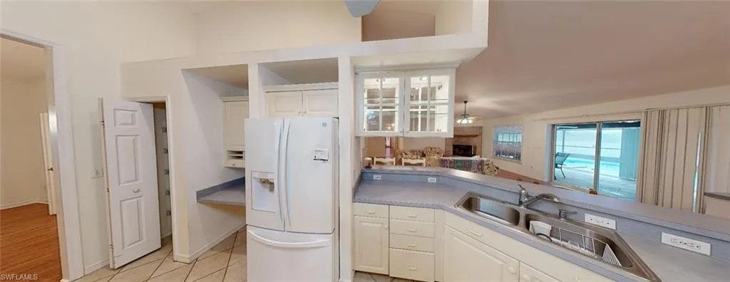 Kitchen featuring white refrigerator with ice dispenser, a fireplace, light hardwood / wood-style flooring, white cabinetry, and ceiling fan