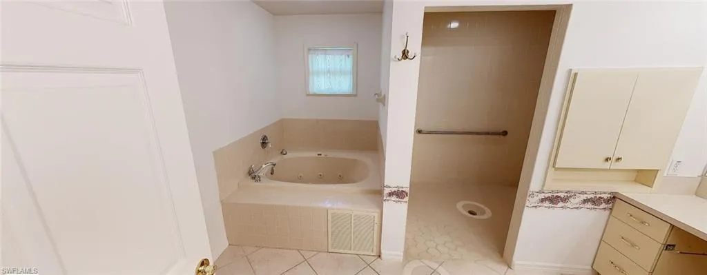 Bathroom with vanity, a relaxing tiled tub, and tile patterned flooring