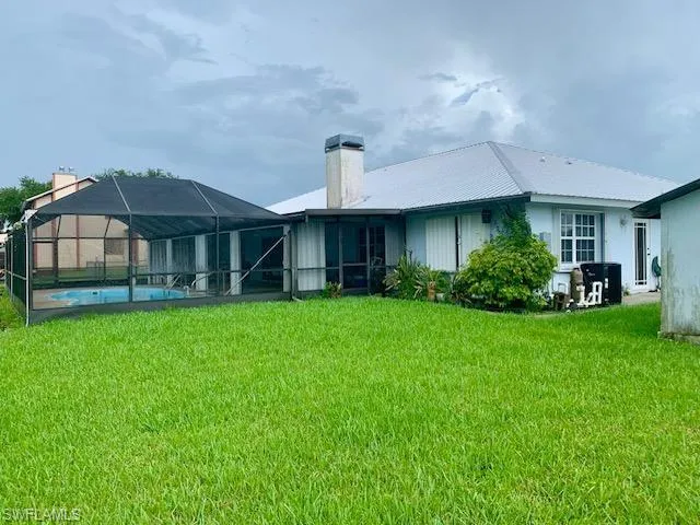 Rear view of house with a lawn and a lanai