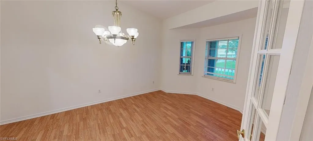 Empty room featuring lofted ceiling, a chandelier, and light hardwood / wood-style floors