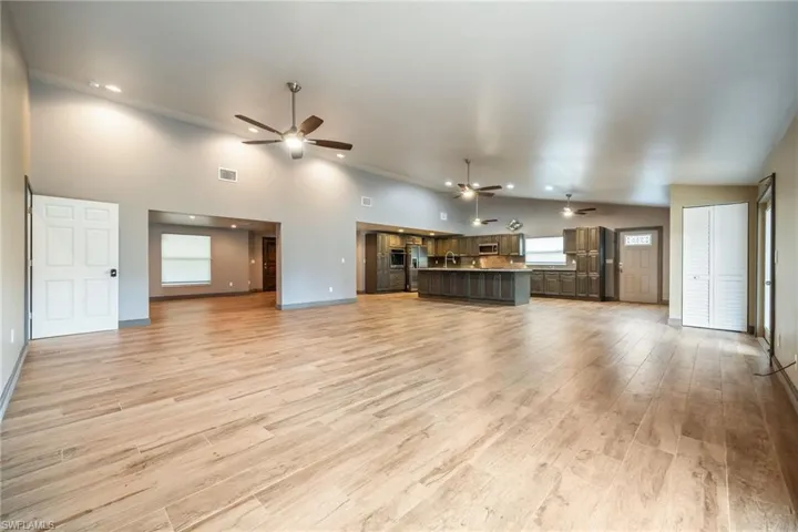 Unfurnished living room featuring light wood finished floors, ceiling fan, and high vaulted ceiling