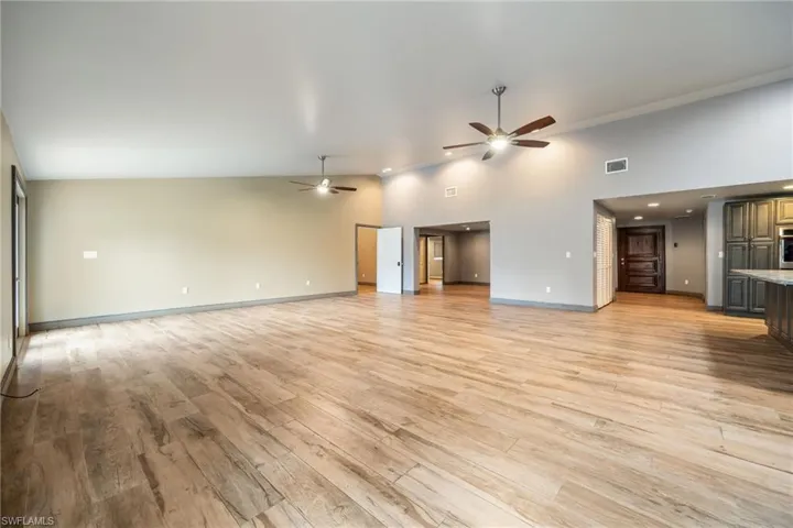 Unfurnished living room featuring light wood-style floors, a ceiling fan, and lofted ceiling