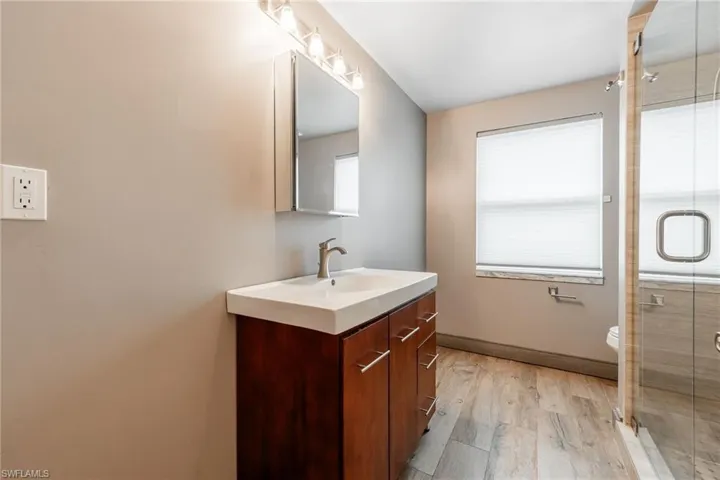 Full bath featuring vanity, light wood-style floors, and a shower stall