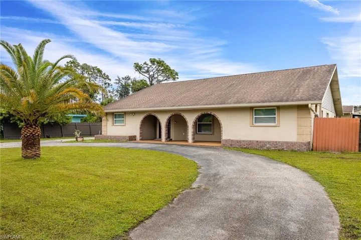 Single story home featuring curved driveway, a shingled roof, brick siding, and stucco siding