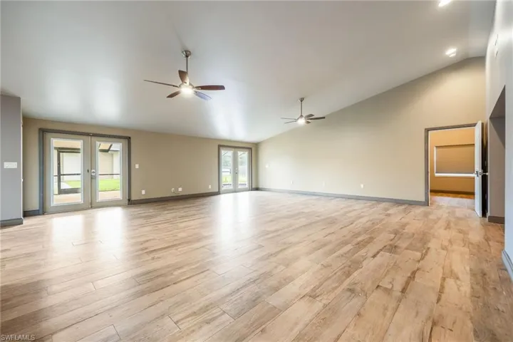 Spare room with light wood finished floors, french doors, ceiling fan, and high vaulted ceiling