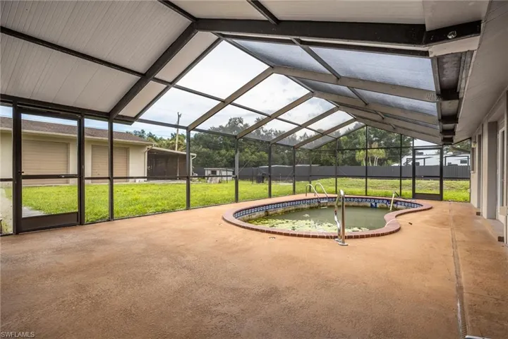 View of swimming pool with a sunroom, a yard, a patio, and a lanai
