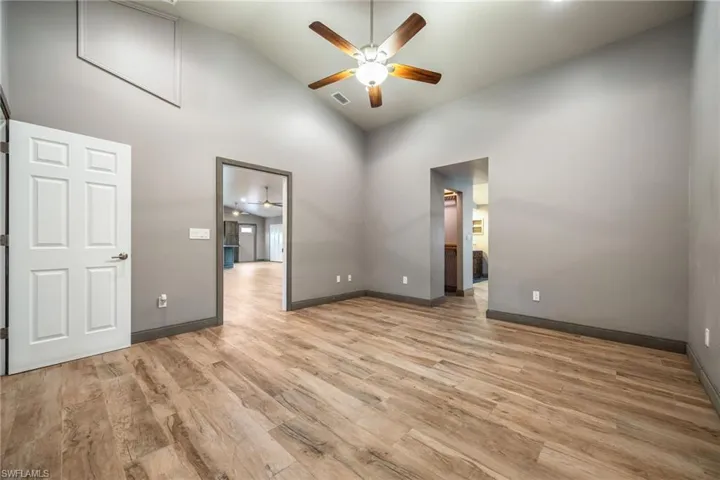 Unfurnished room with light wood-style floors, ceiling fan, and high vaulted ceiling