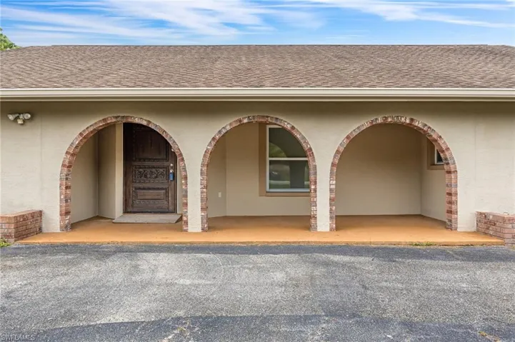 Doorway to property featuring stucco siding and roof with shingles