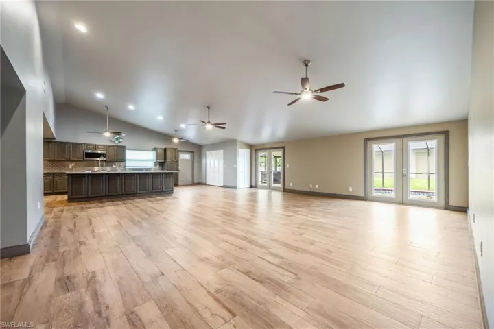 Unfurnished living room with a ceiling fan, light wood-style floors, vaulted ceiling, french doors, and recessed lighting