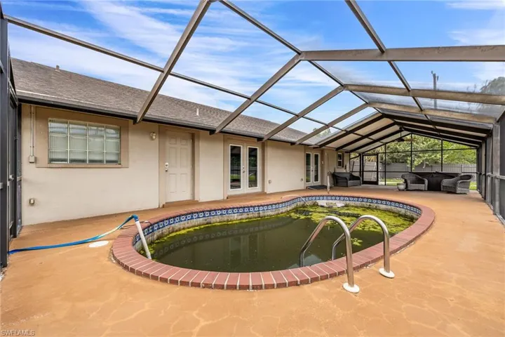 Outdoor pool featuring a sunroom, glass enclosure, a patio, and french doors