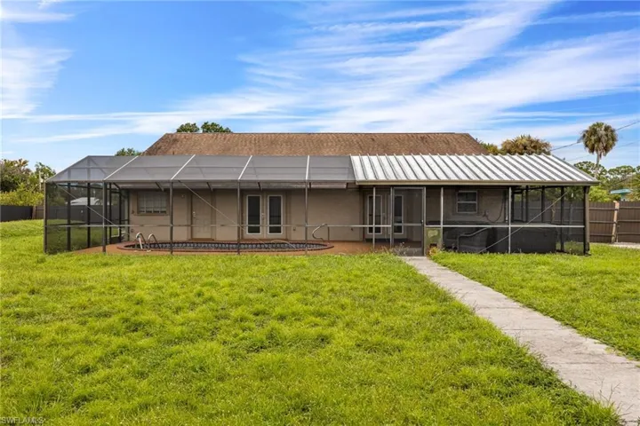 Back of house with a sunroom, a yard, and a lanai