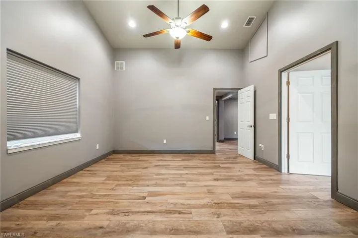 Unfurnished room with light wood-style floors, a ceiling fan, a towering ceiling, and recessed lighting