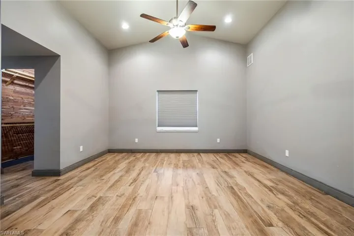 Master bedroom with light wood-style floors, vaulted ceiling, ceiling fan, and recessed lighting