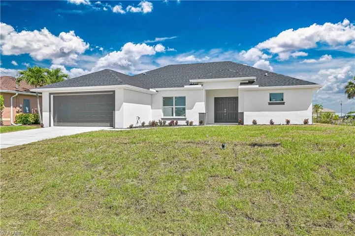 Prairie-style home featuring stucco siding, a garage, driveway, and a front yard