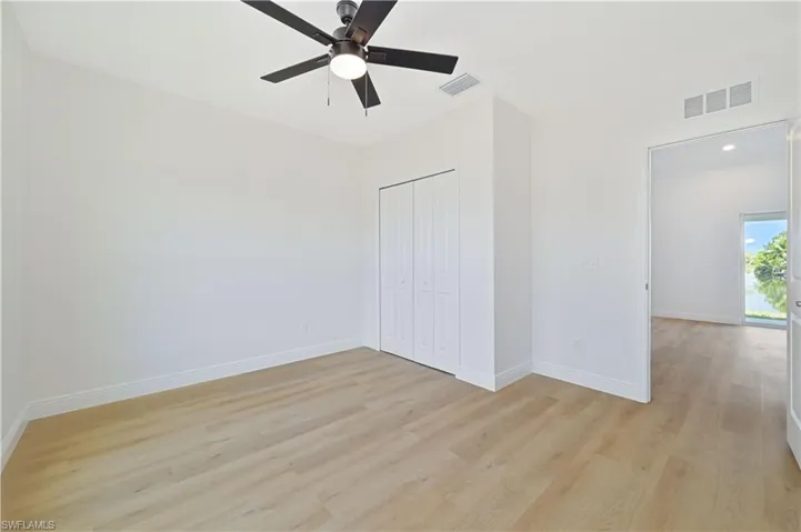Guest bedroom/den/office with light wood finished floors, baseboards, a closet, and a ceiling fan