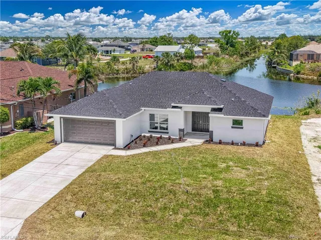 View of front of home featuring a water view, a garage, roof with shingles, and a front yard