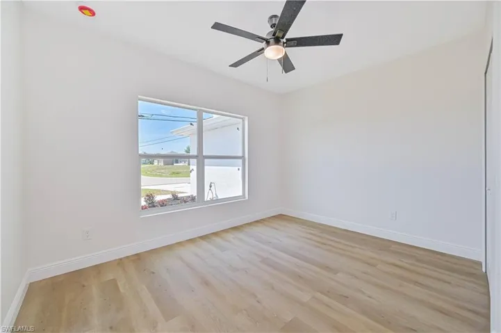 Guest bedroom with light wood-type flooring, baseboards, and a ceiling fan