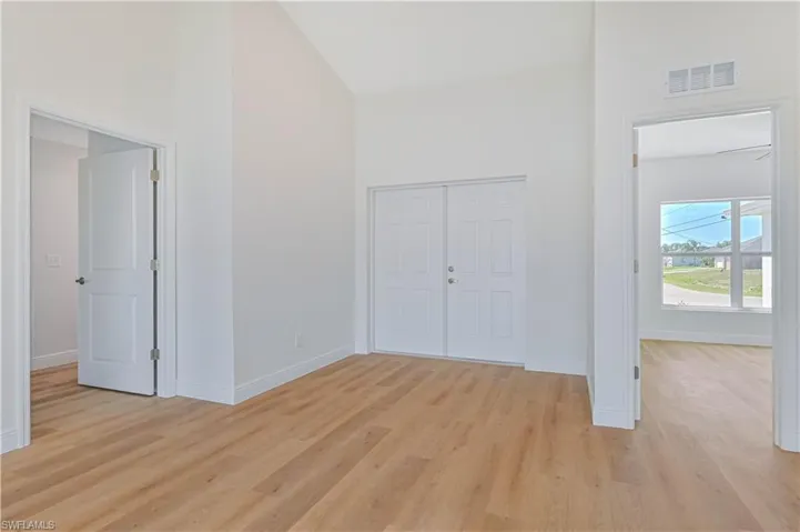Foyer entrance featuring high vaulted ceiling, light wood-style flooring, and baseboards