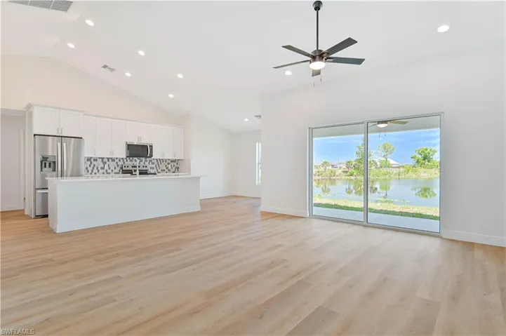 Living room with recessed lighting, a ceiling fan, light wood-type flooring, high vaulted ceiling, and baseboards