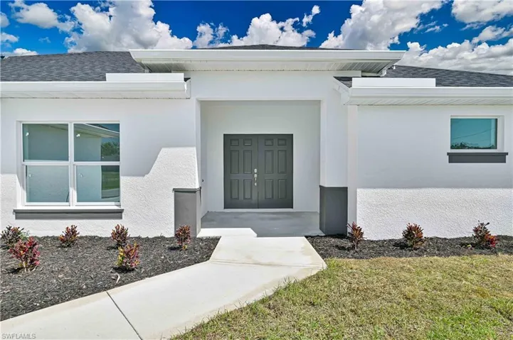 Entrance to property featuring stucco siding and roof with shingles
