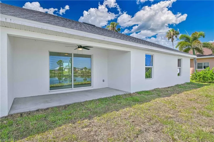 Rear view of house featuring a lawn, a ceiling fan, a patio and stucco siding