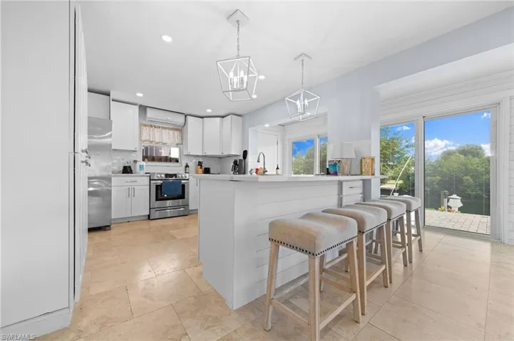 Kitchen featuring a kitchen island, pendant lighting, white cabinetry, appliances with stainless steel finishes, and backsplash