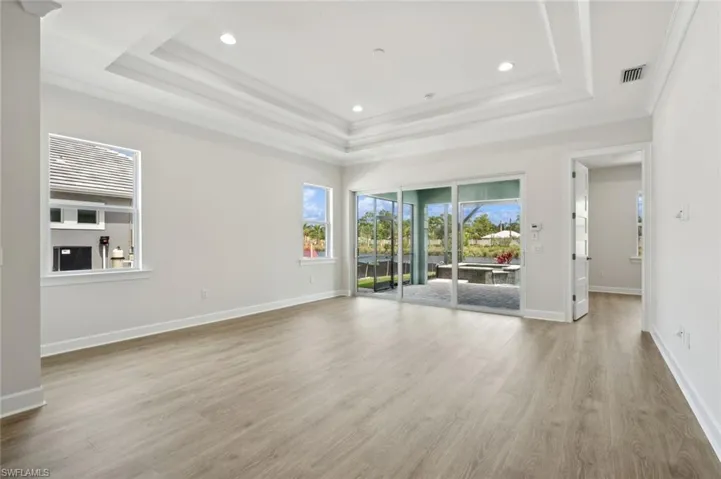 Spare room with a tray ceiling, ornamental molding, and light wood-type flooring