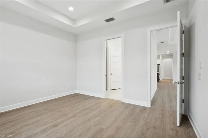 Unfurnished bedroom with a tray ceiling and light wood-type flooring