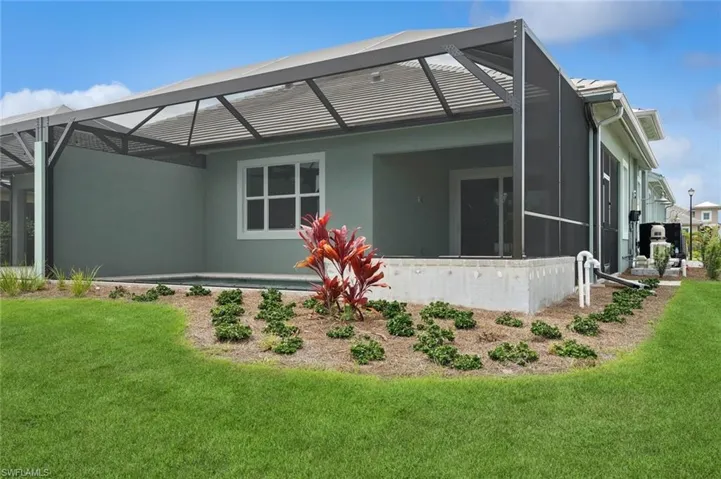 Rear view of house featuring a lawn and glass enclosure