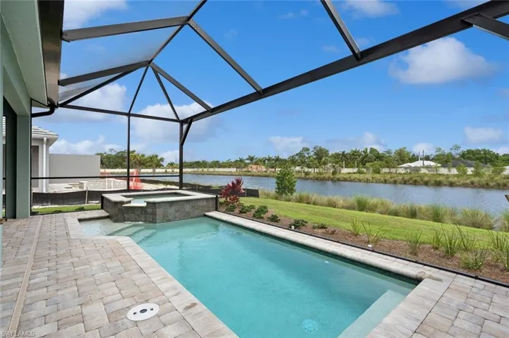 View of swimming pool with a patio, a lanai, an in ground hot tub, and a water view