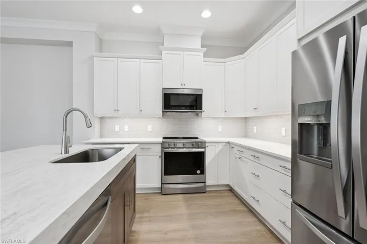 Kitchen featuring stainless steel appliances, light hardwood / wood-style floors, tasteful backsplash, and sink