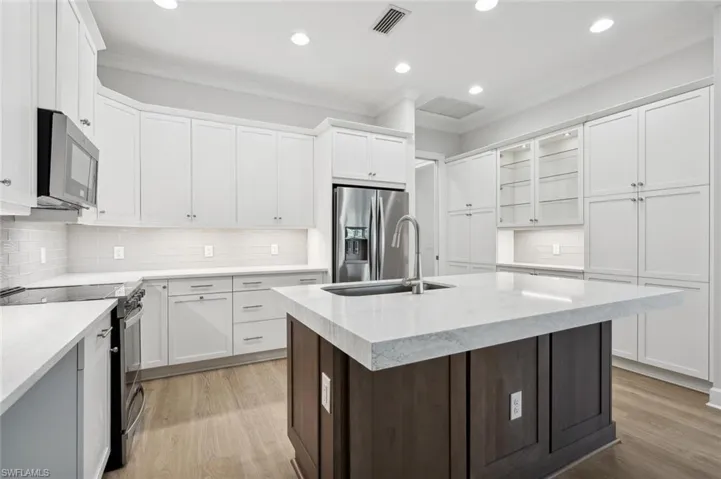 Kitchen featuring light hardwood / wood-style floors, white cabinets, backsplash, and appliances with stainless steel finishes