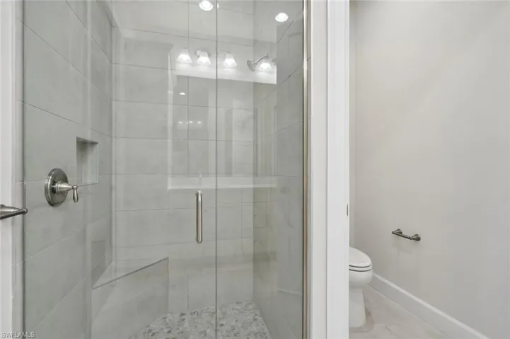 Bathroom with a shower with door, tile flooring, and toilet