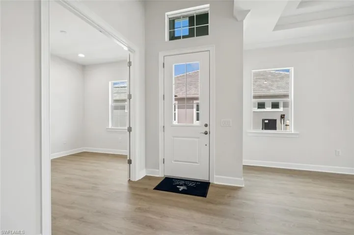 Entrance foyer with light hardwood / wood-style floors and a raised ceiling