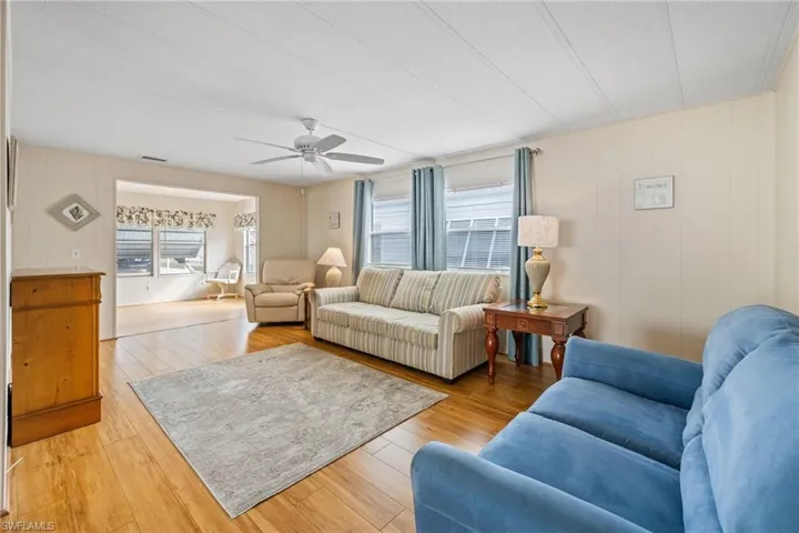 Living room featuring a ceiling fan, wood-type flooring, plenty of natural light, and wooden walls