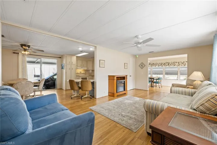 Living area featuring a ceiling fan, light wood-style flooring, and wooden walls