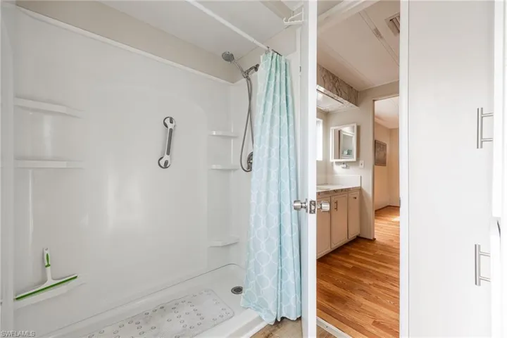 Full bath featuring light wood-style floors, a shower stall, and vanity