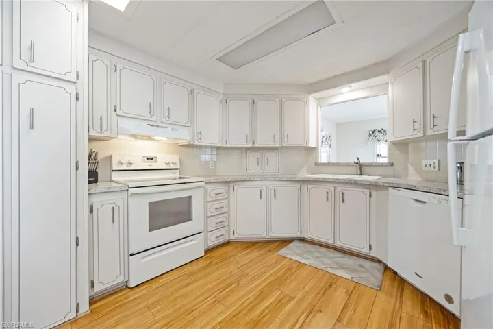 Kitchen featuring white appliances, white cabinetry, and light countertops
