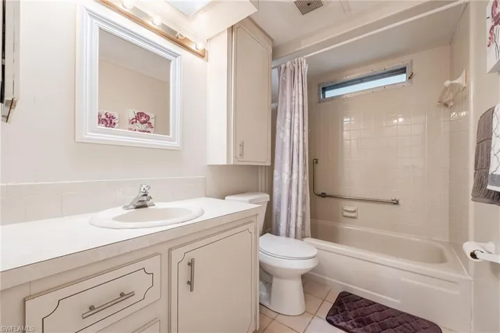Full bath featuring vanity, shower / tub combo, and light tile patterned floors