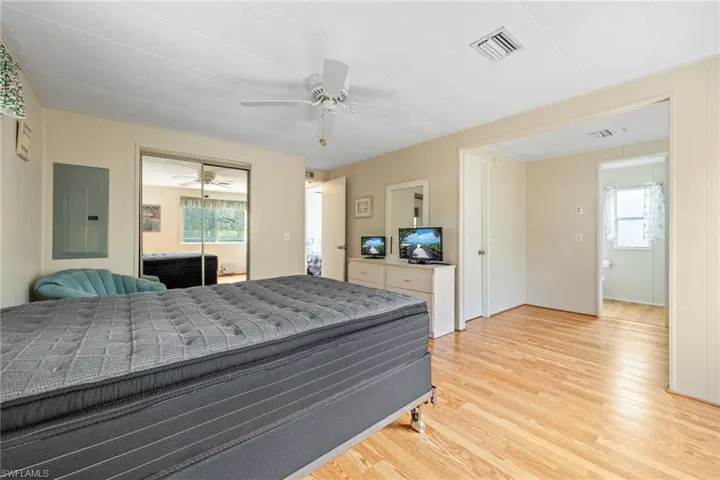 Bedroom with electric panel, light wood-style floors, ceiling fan, and a closet