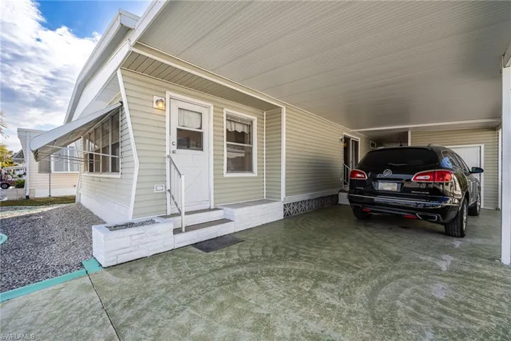 View of exterior entry featuring a carport and covered porch