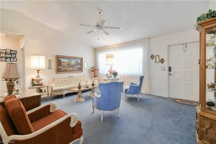 Living room with carpet floors, vaulted ceiling, a ceiling fan