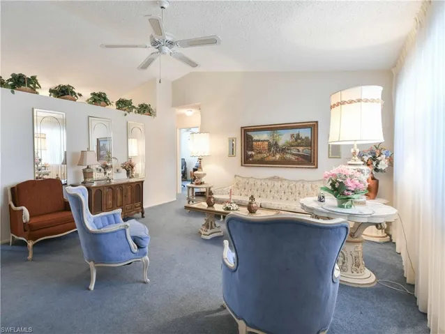 Living area with carpet, ceiling fan, vaulted ceiling