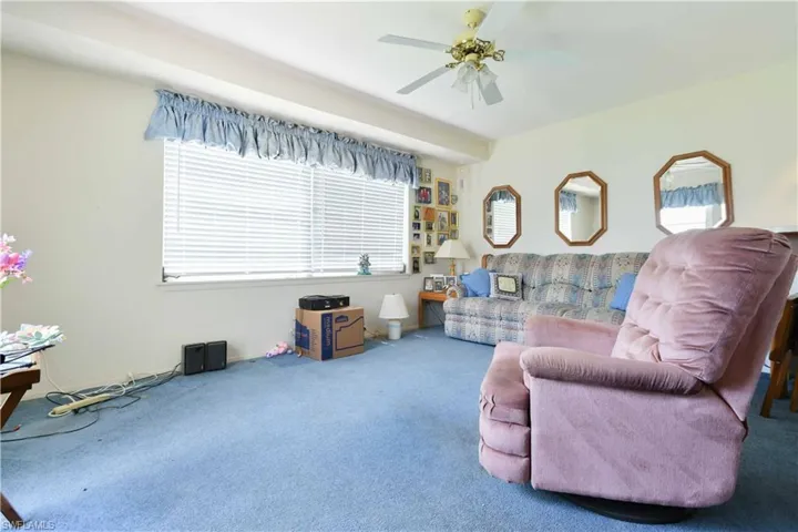 Carpeted living area featuring ceiling fan