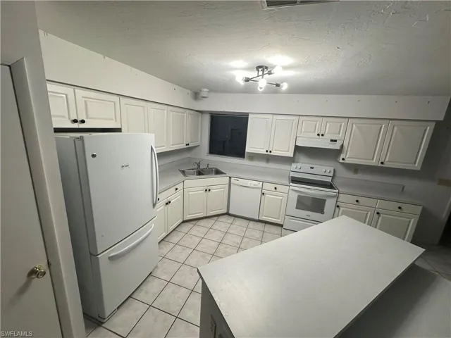 Kitchen featuring white cabinets, sink, white appliances, and light tile patterned floors