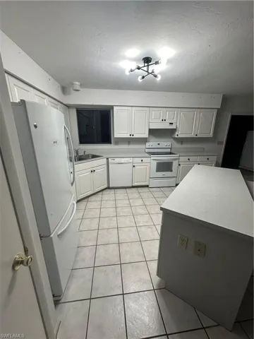 Kitchen with light tile patterned floors, dishwasher, fridge, stove, and sink