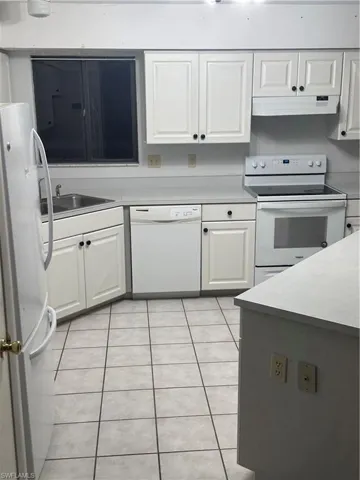 Kitchen with range, extractor fan, white cabinets, white dishwasher, and refrigerator