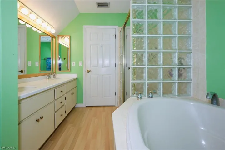 Double vanities, jetted tub, glass block shower and toilet behind separate door.