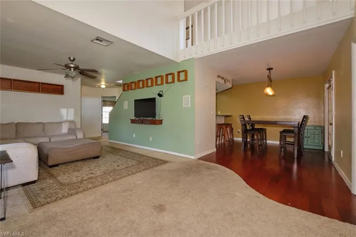 Living room/dining area with kitchen off to the left.  Double doors lead to the salt-water pool, yard and lanai.  Notice the loft up above.